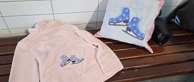 Embroidered ice skate design featured on a hoodie and a pillow.