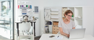 woman on laptop with Brother PR1055x embroidery machine