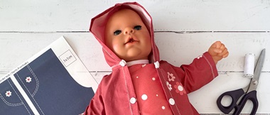 Doll with red clothes and printed pattern pieces.
