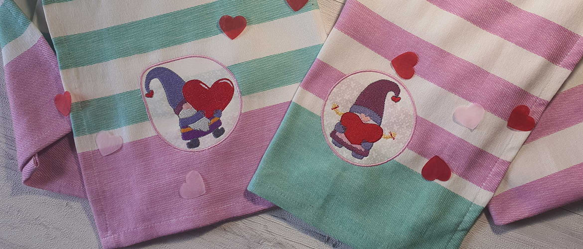 Two embroidered gnomes on pink and green striped fabric