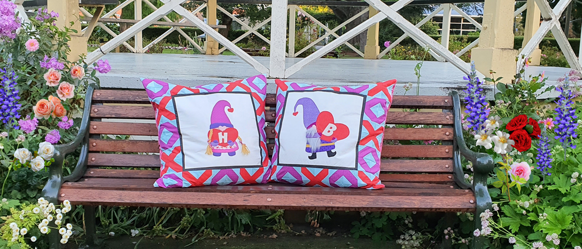 Two colourful love gnome cushions on park bench