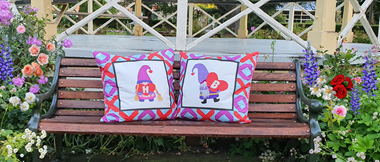 Two colourful love gnome cushions on park bench