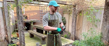 man in dark green apron in garden