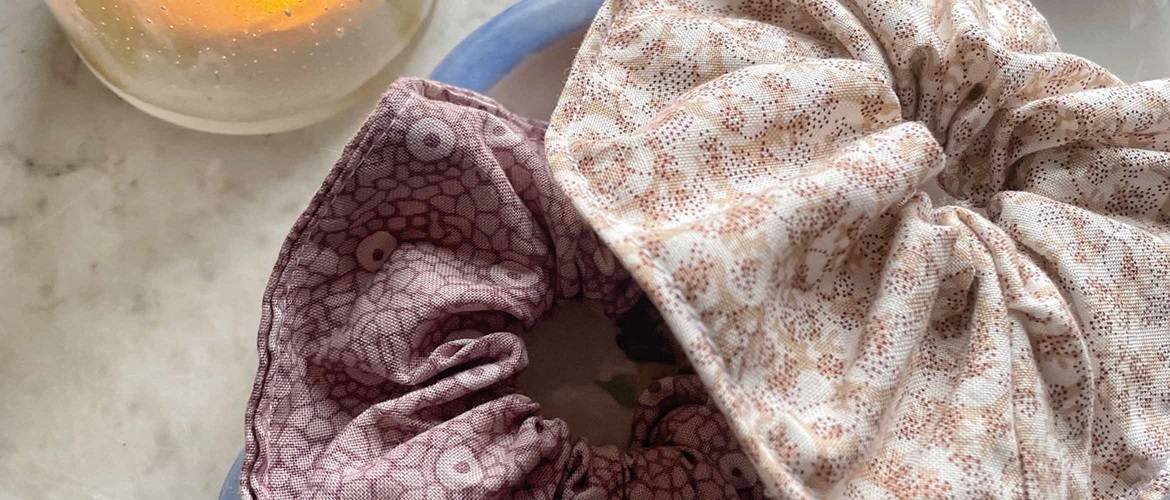 two brown floral hair scrunchies on a blue plate