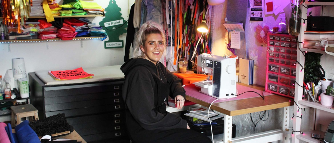 Woman sits at wooden desk with Brother sewing machine