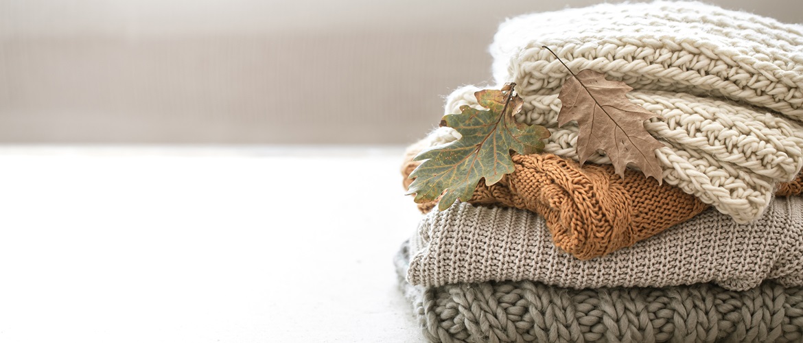 Stack of three knitted jumpers neutral pastels
