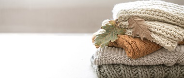 Stack of three knitted jumpers neutral pastels