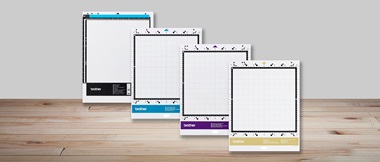 Multiple white ScanNCut cutting mats on wooden desk