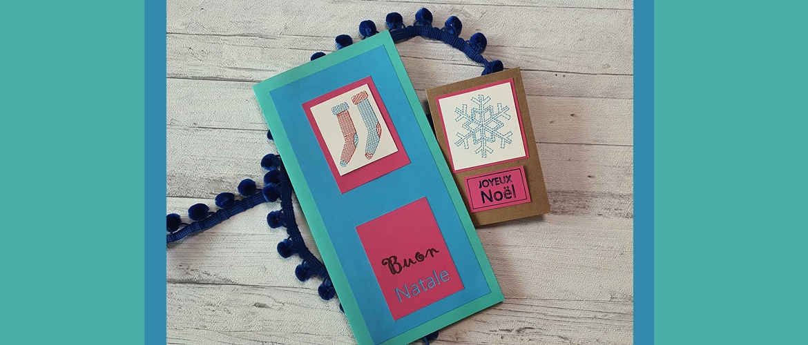 Two christmas paper cards with embroidered bits on white wood