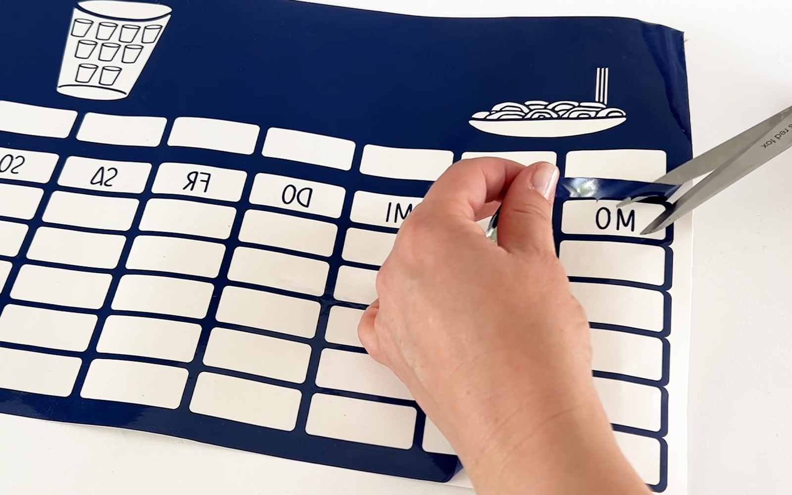 hands cutting weeded vinyl from ScanNCut weekly planner