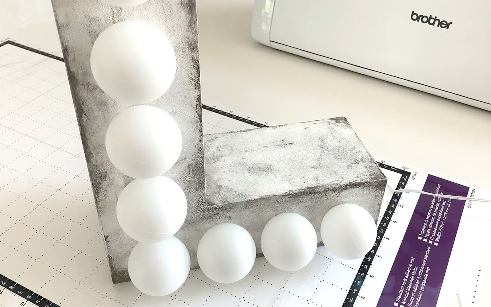 L shaped grey light with exposed lightbulbs in front of ScanNCut