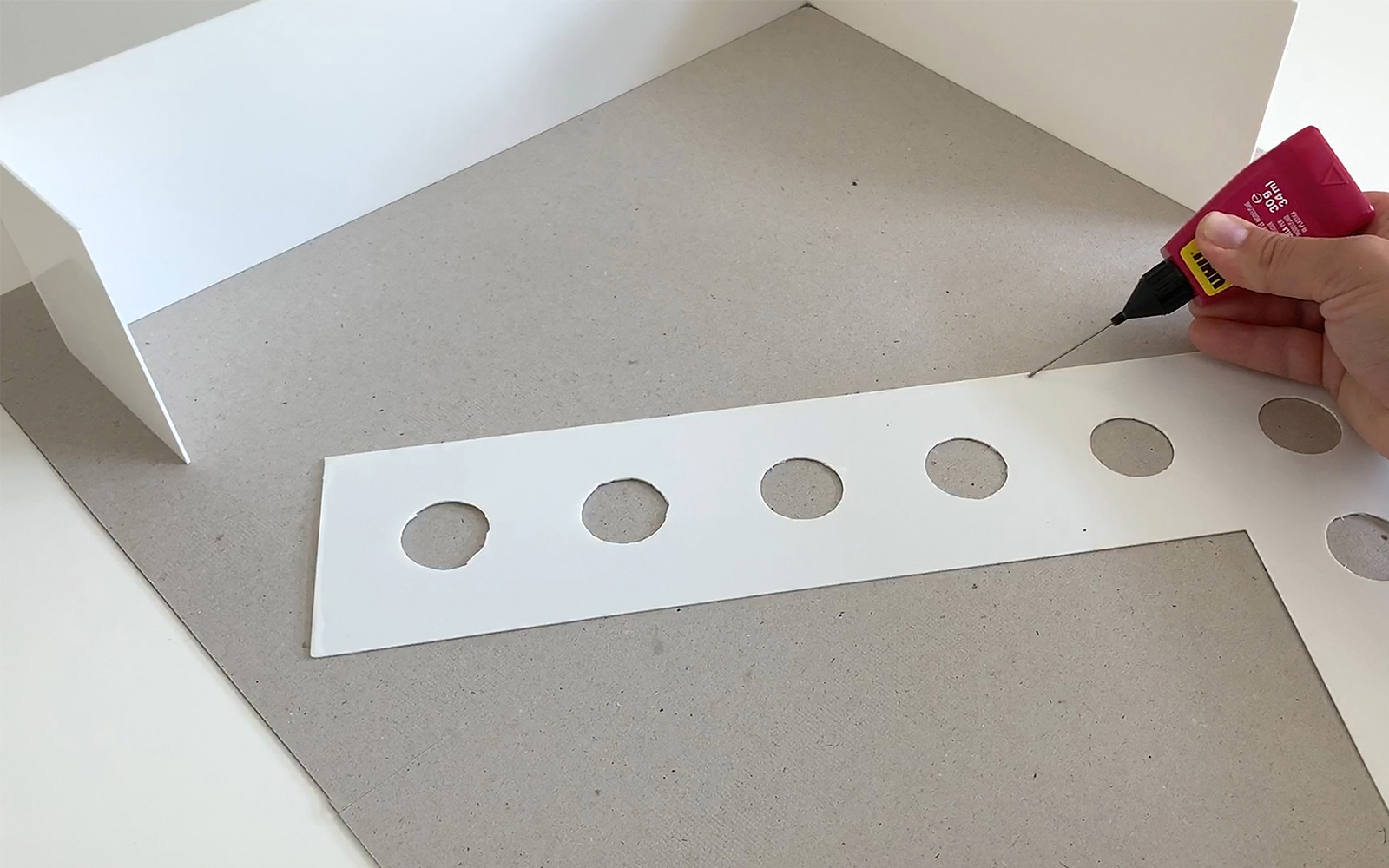 hand tracing modelling glue along edge of L shaped polystyrene