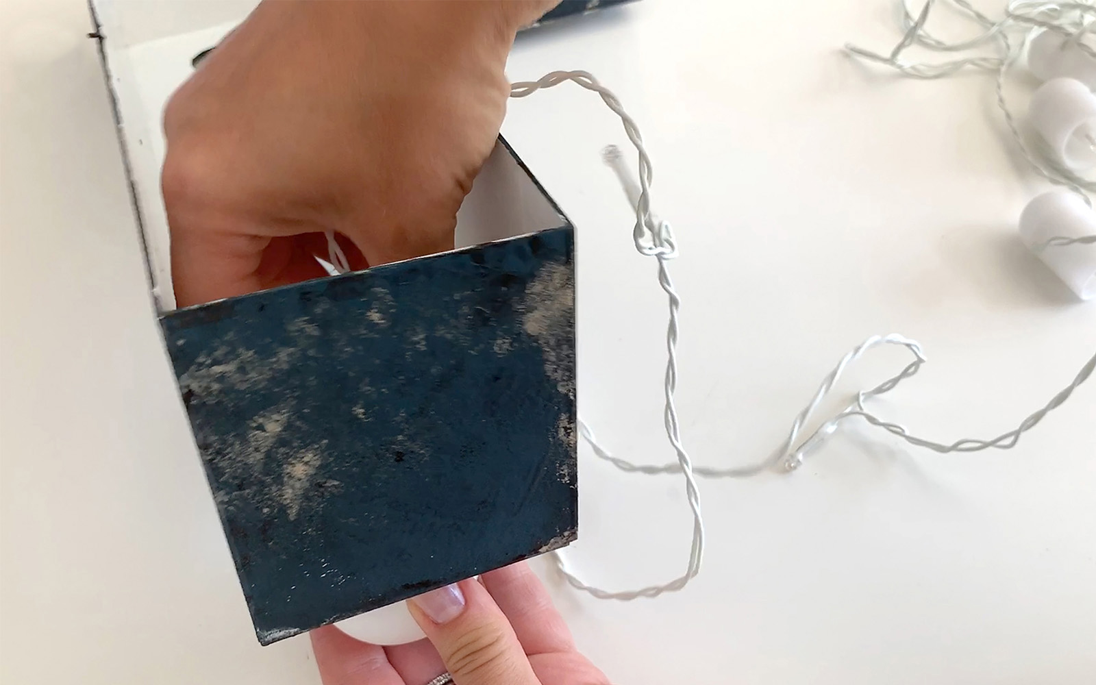 hand holding black box and screwing bulb light in