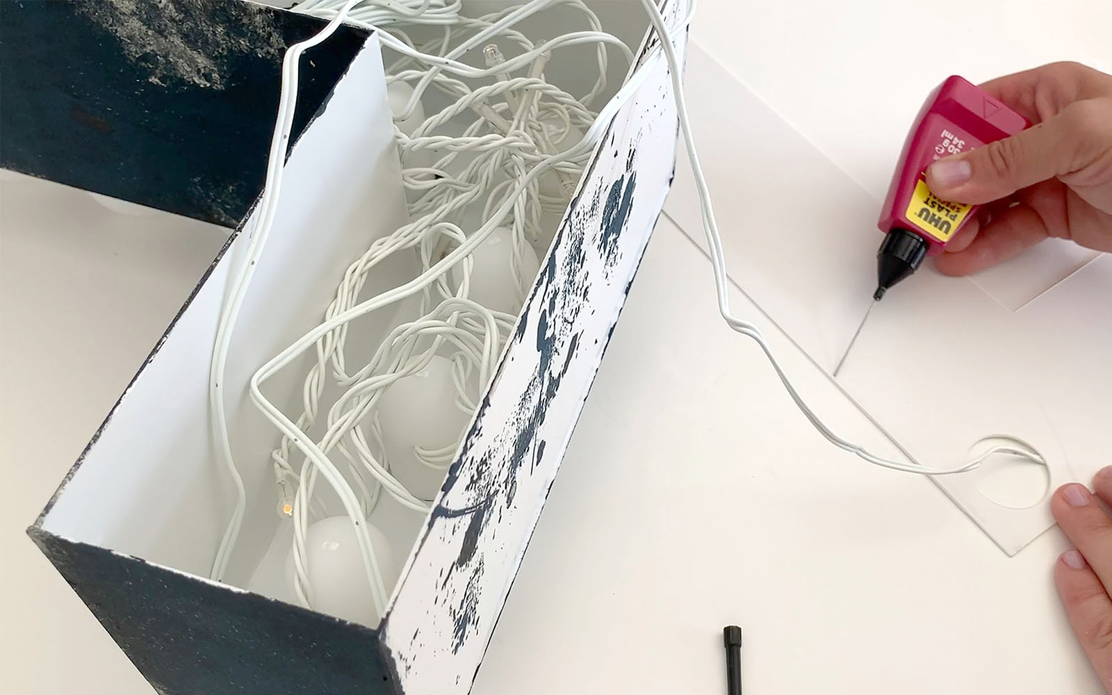 hand putting glue along edge of L shaped white polystyrene shape