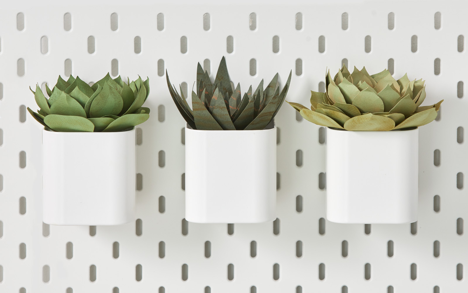 three paper succulents in white pots on pegboard
