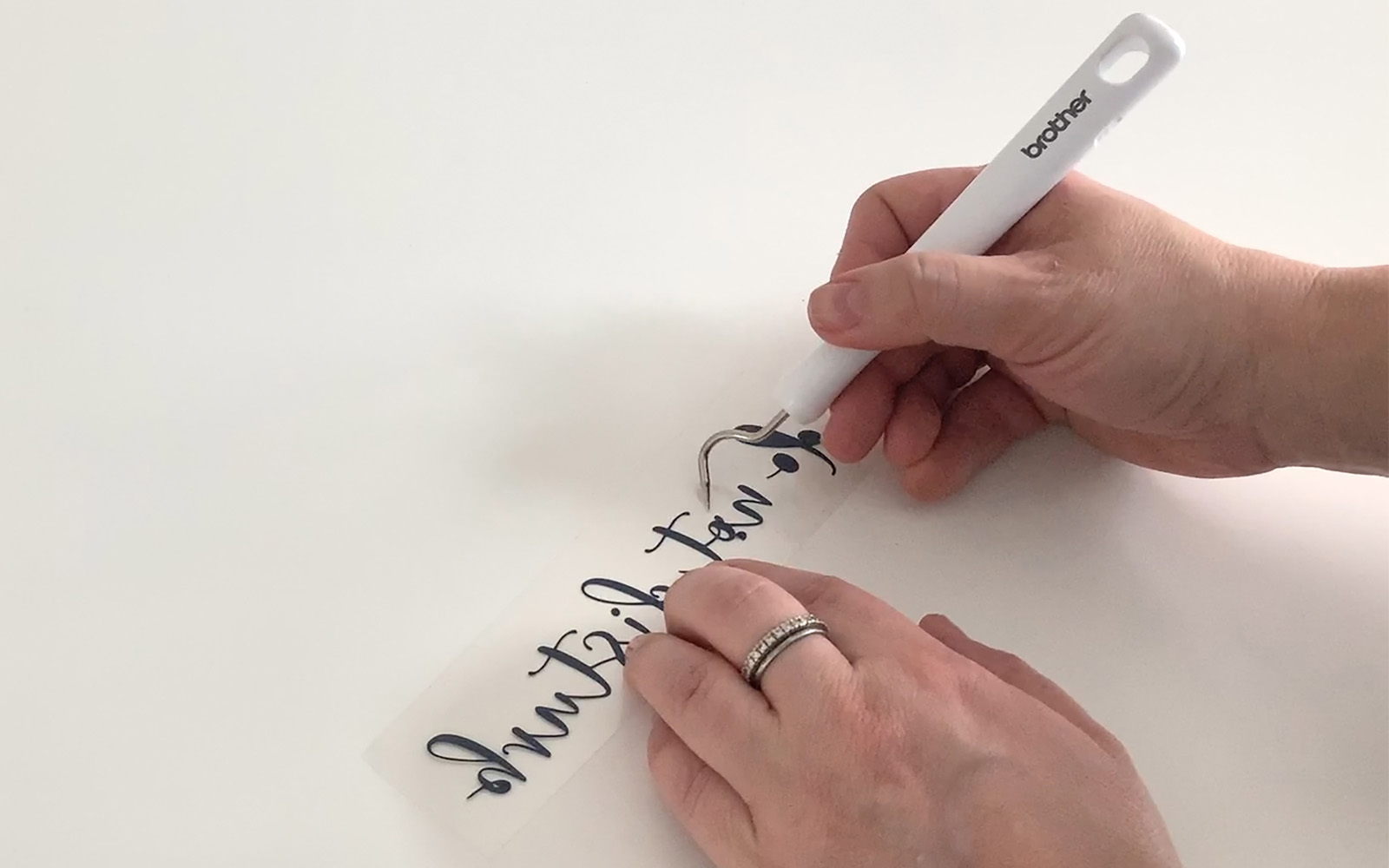 Hand weeding foil from black sticker text with small hook tool