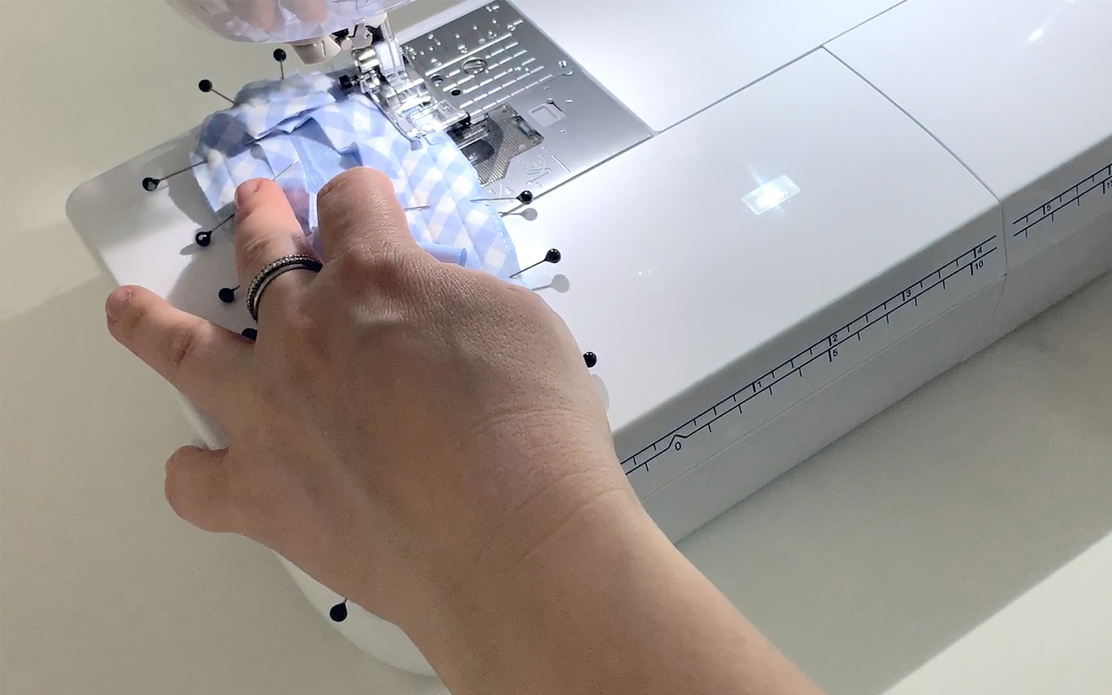 hands spinning blue check bias tape to edge of blue sleeping mask