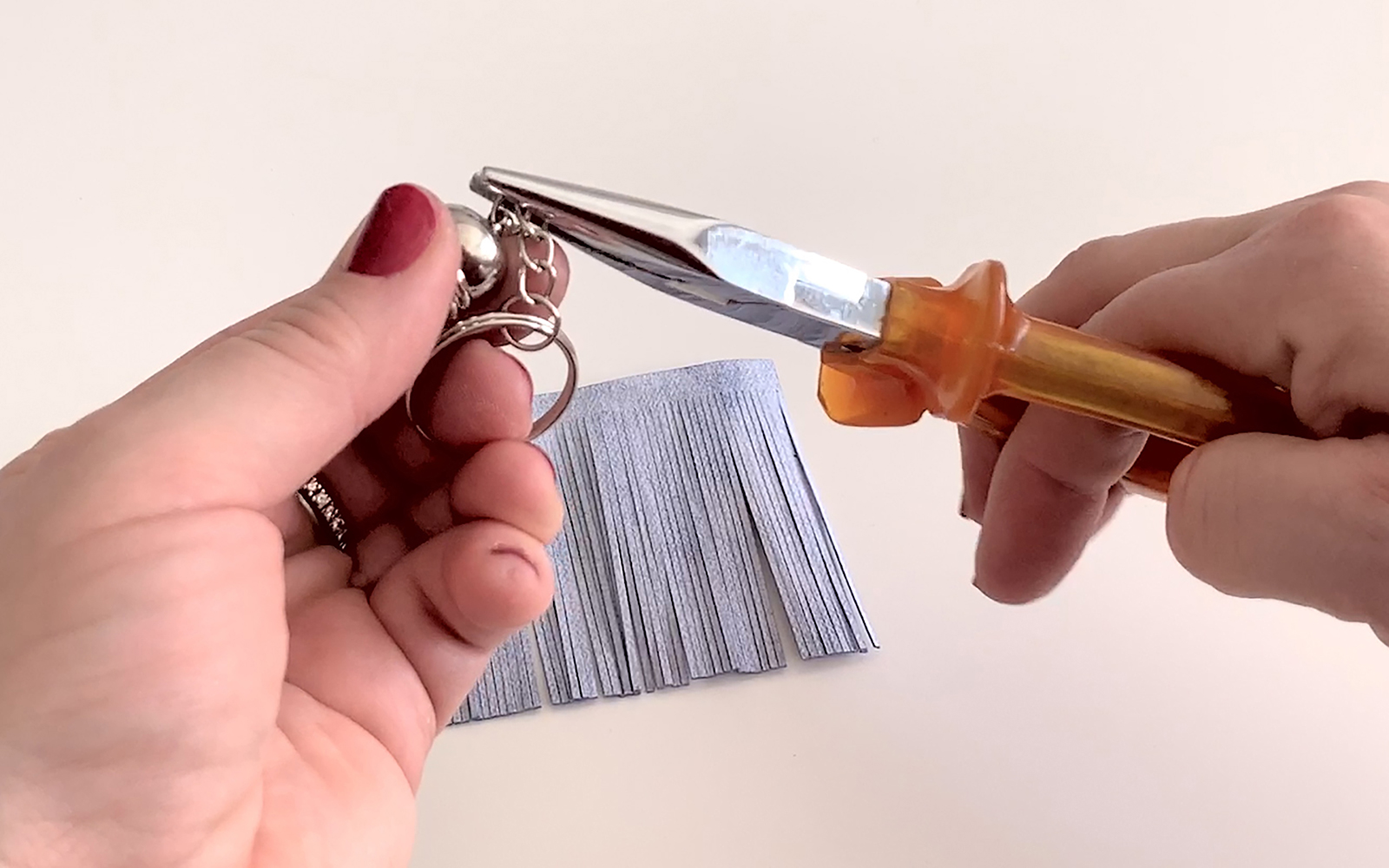 Opening eyelet with pliers, white leather rectangle in background