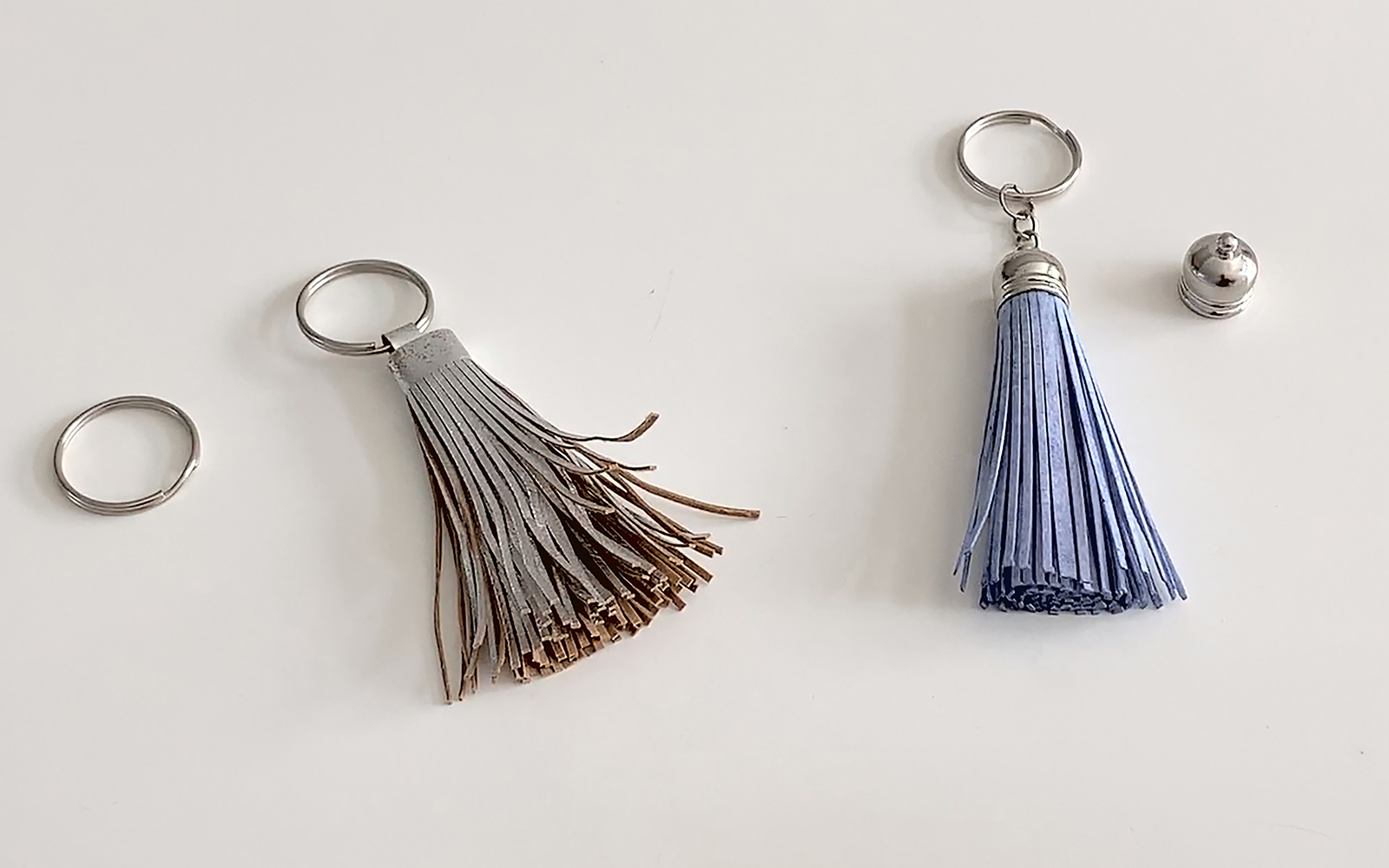 a silver and a blue tasselled key ring next to each other