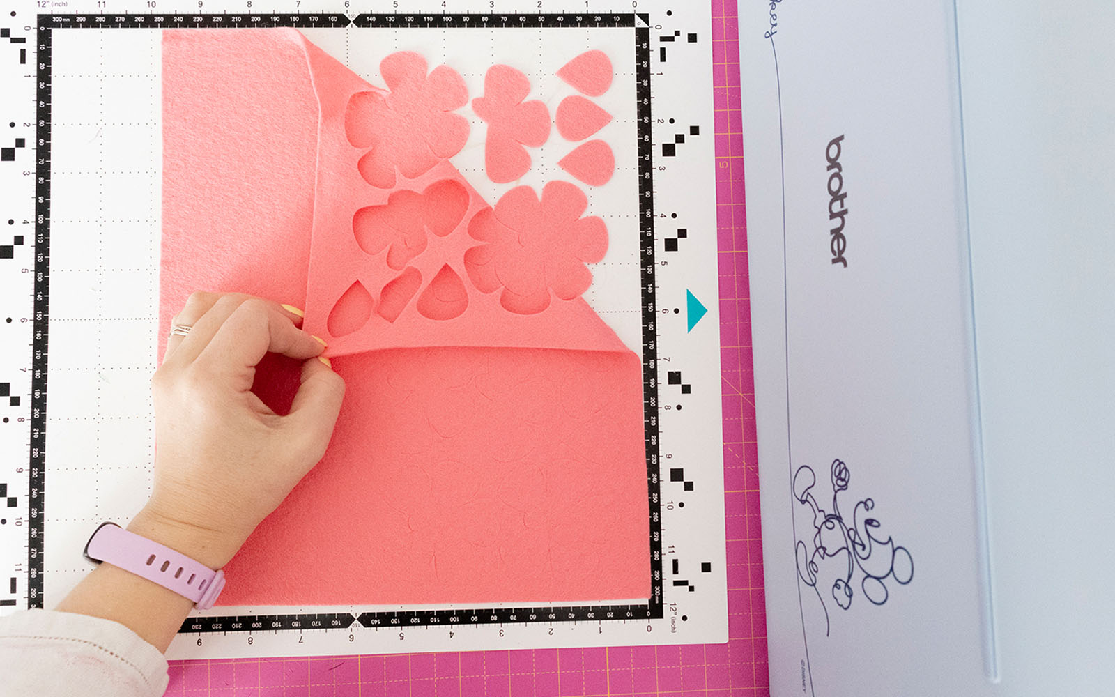 Hand removing pink felt from Brother ScanNCut mat