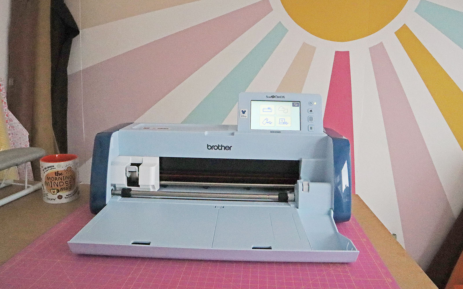 Brother ScanNCut SDX 2250D devant un vinyle mural soleil pastel 
