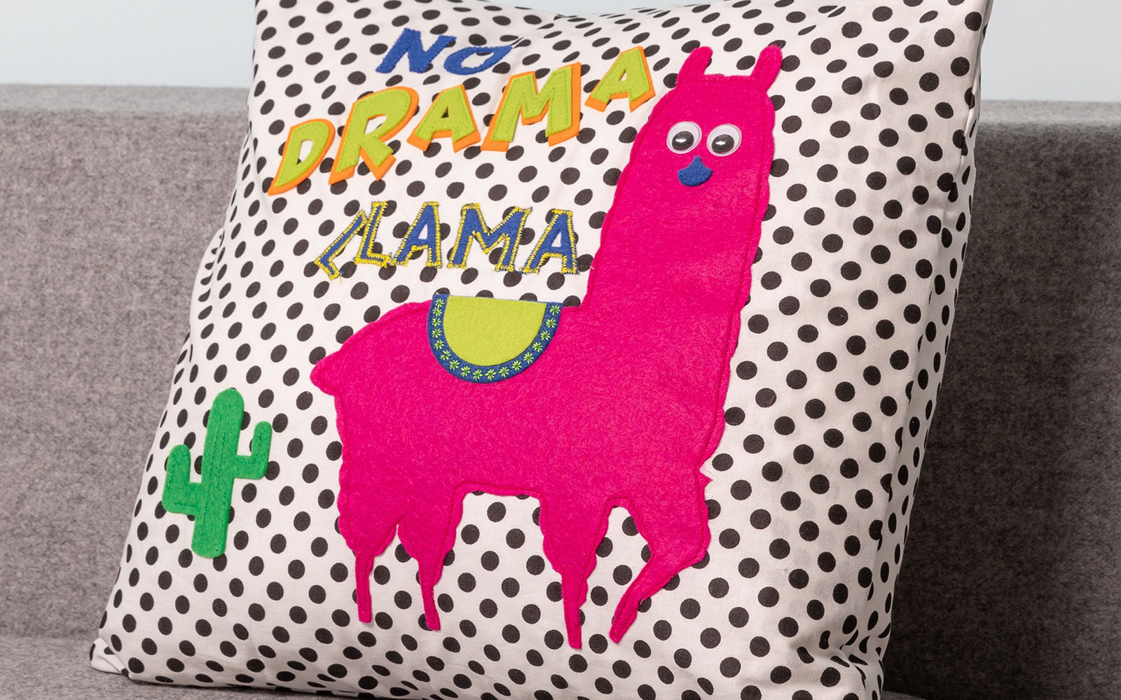 Spotty cushion with pink llama on grey sofa