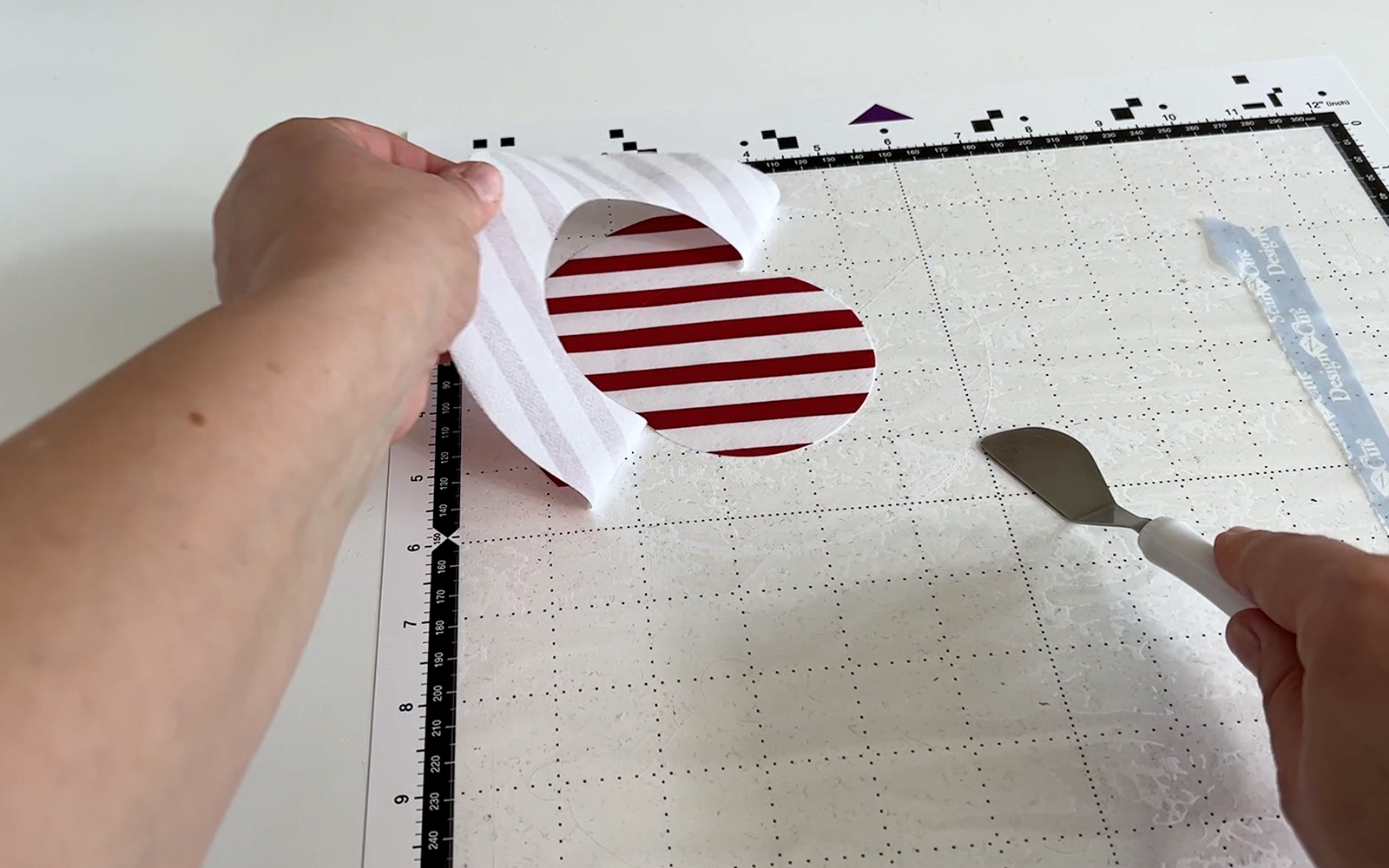 Retrait de la toile cirée du support de découpe pour tissu Brother ScanNCut à l'aide d'une spatule Brother.