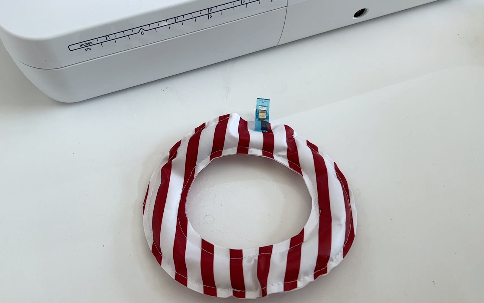 Pièce en forme de O en toile cirée rayée rouge et blanche devant la machine à balancer Brother