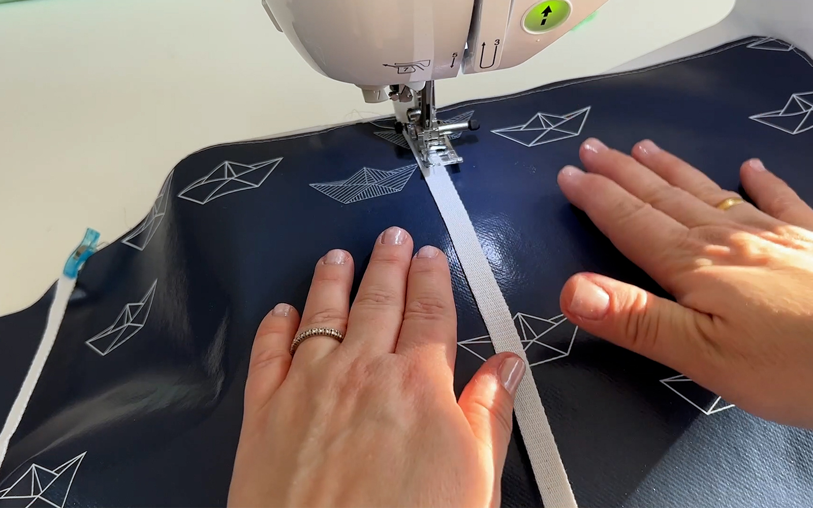 Sewing white tape in straight lines onto blue oilcloth with Brother sewing machine