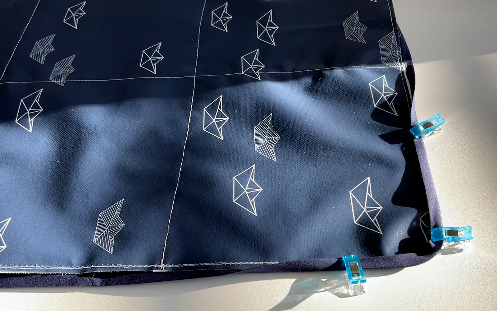 Bevestigen van blauwe biaisband rond olieverf tic-tac-toe snijmat met klemmetjes