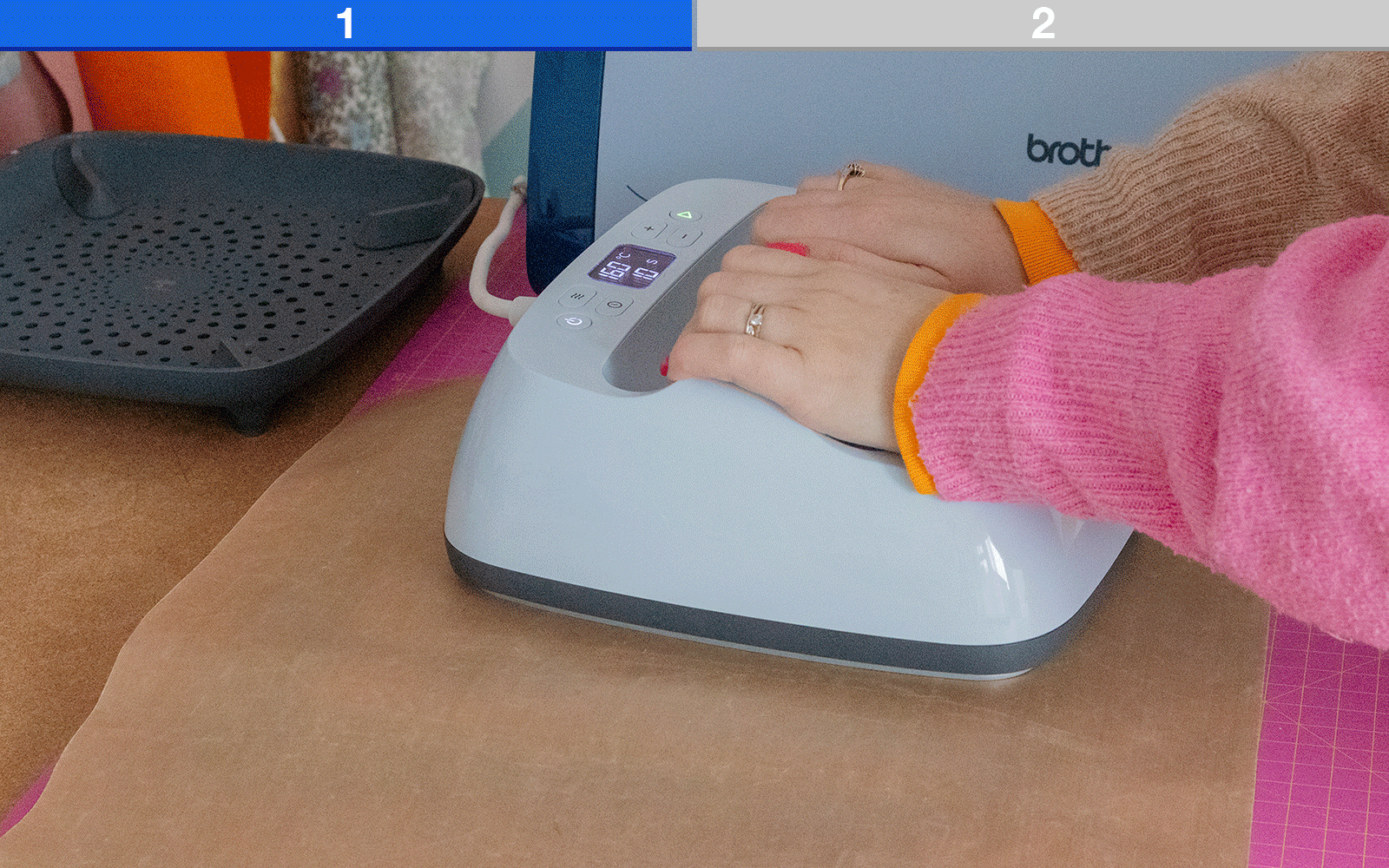 Hands holding a heat press on top of the wooden sign with HTV