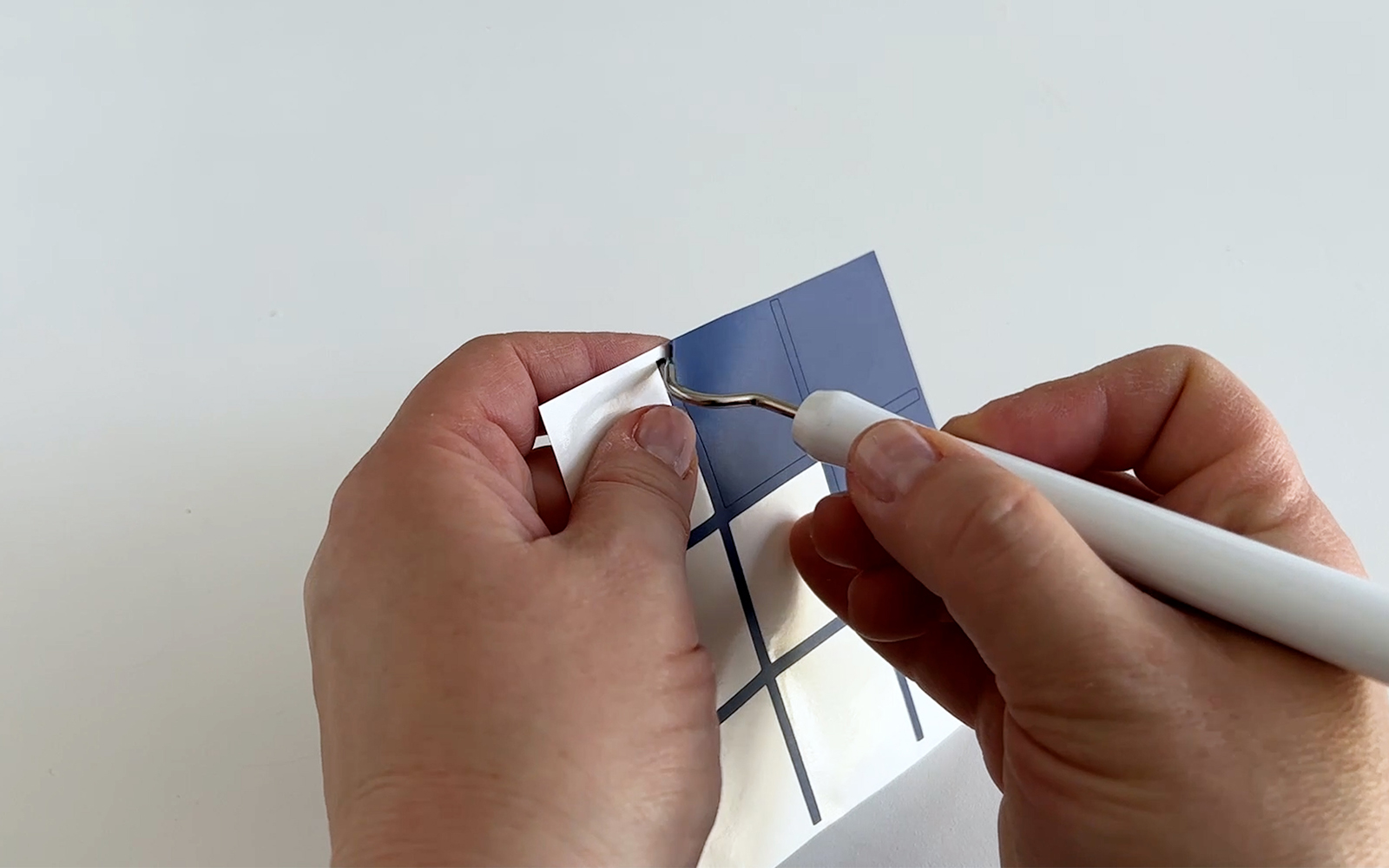 Dark blue vinyl being weeded by hand into grid shape for tic-tac-toe board