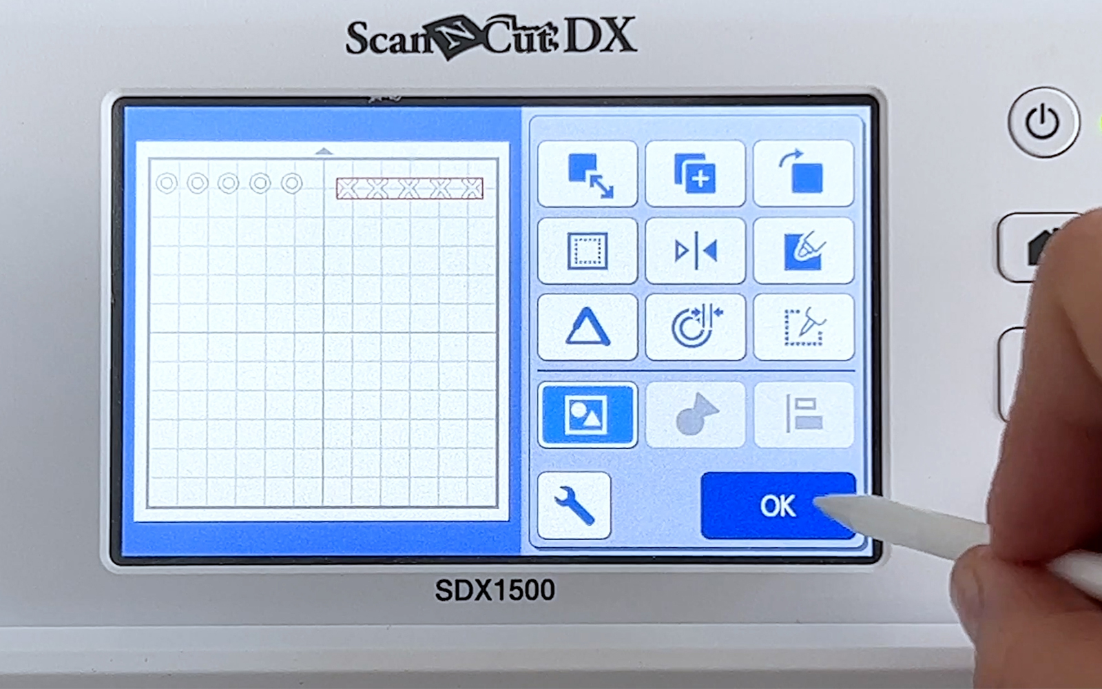 Ok button on ScanNCut SDX1500 touchscreen being pressed with stylus pen