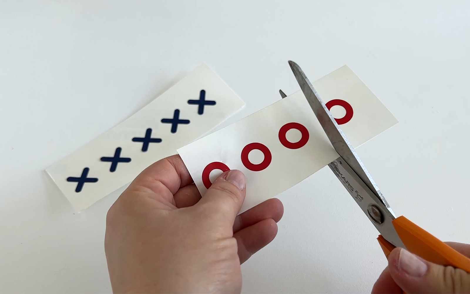 Borduurpatronen van blauw vinyl X en rood vinyl O worden gesneden met een schaar