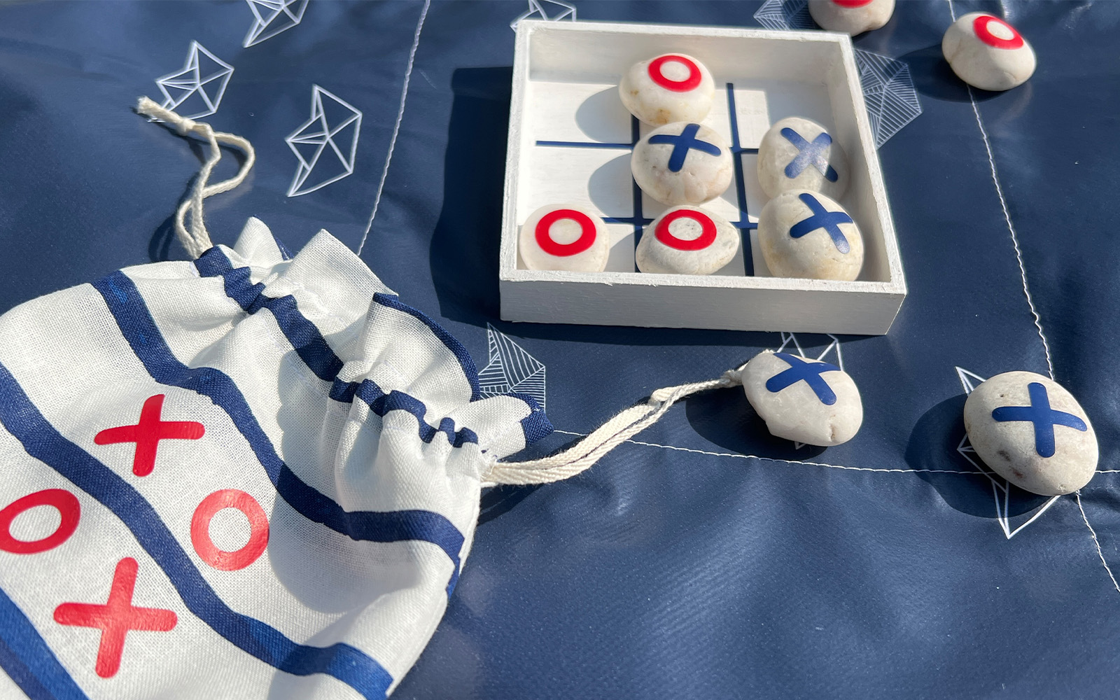 Jeu de morpion de voyage bleu et rouge dont les motifs ont été dessinés par missredfox. 