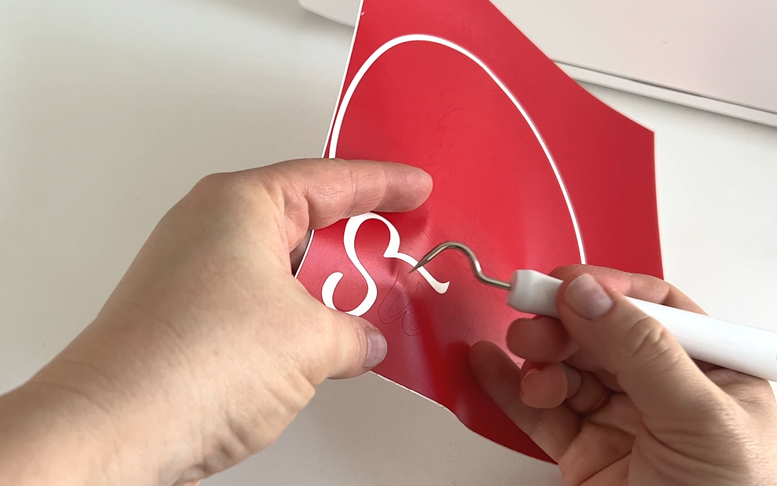 Red craft vinyl being weeded with Brother ScanNCut weeding hook tool