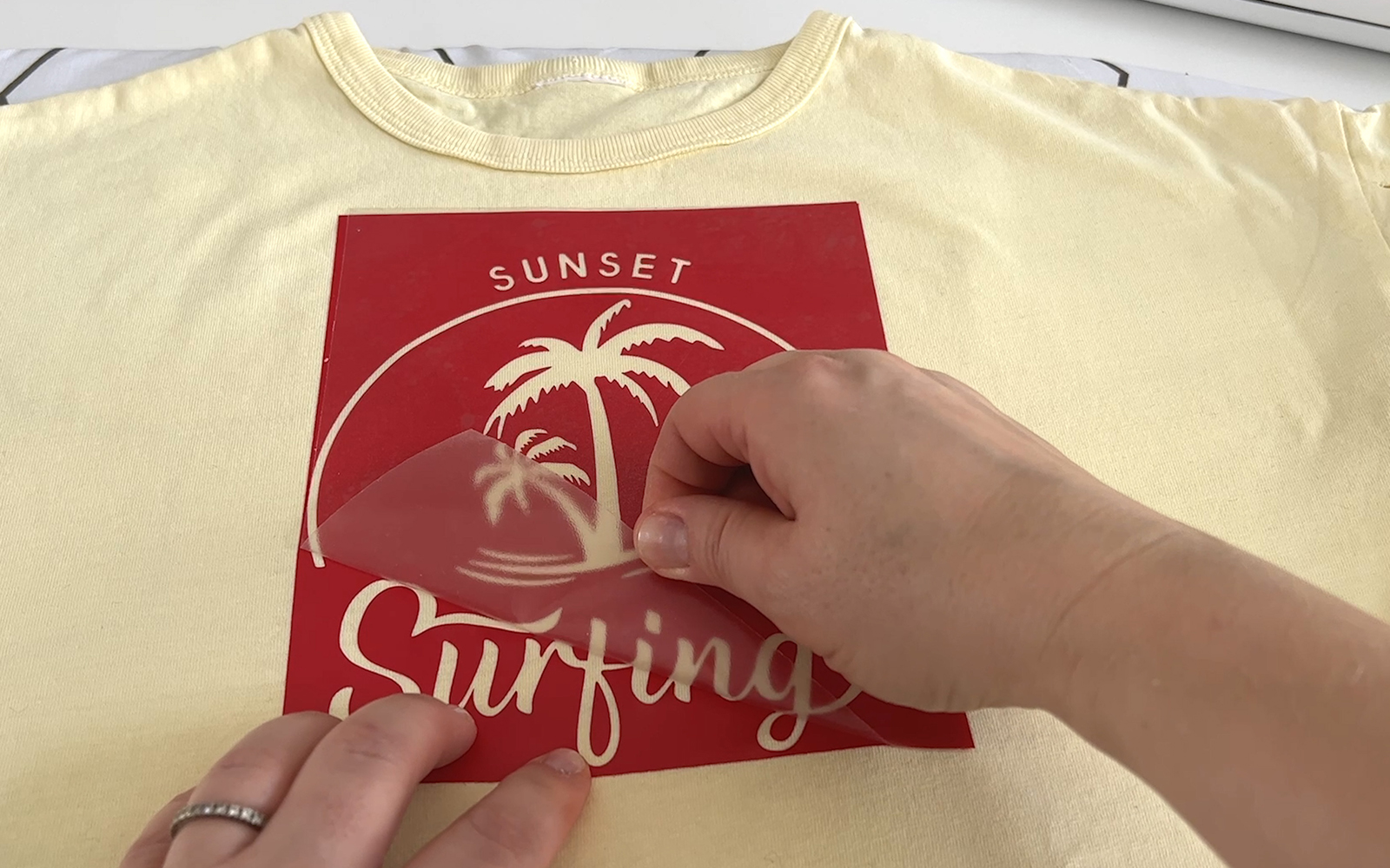 Transfer vinyl being removed from weeded vinyl design