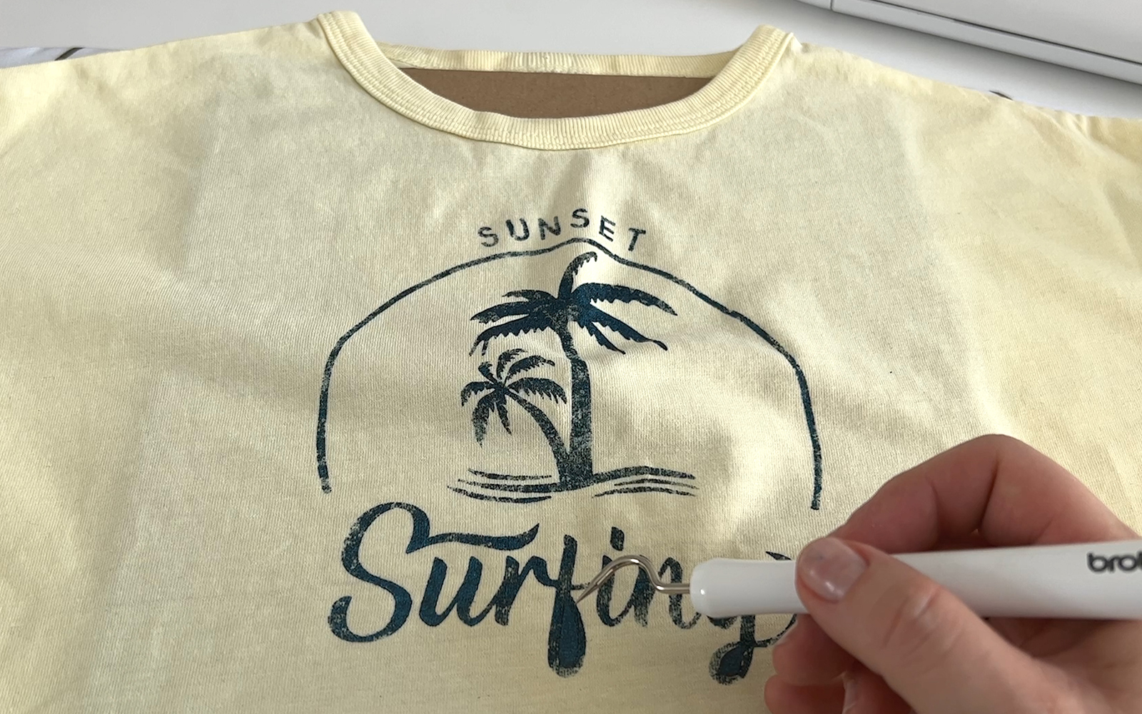 Surfing design pieces being removed from shirt with Brother weeding hook tool
