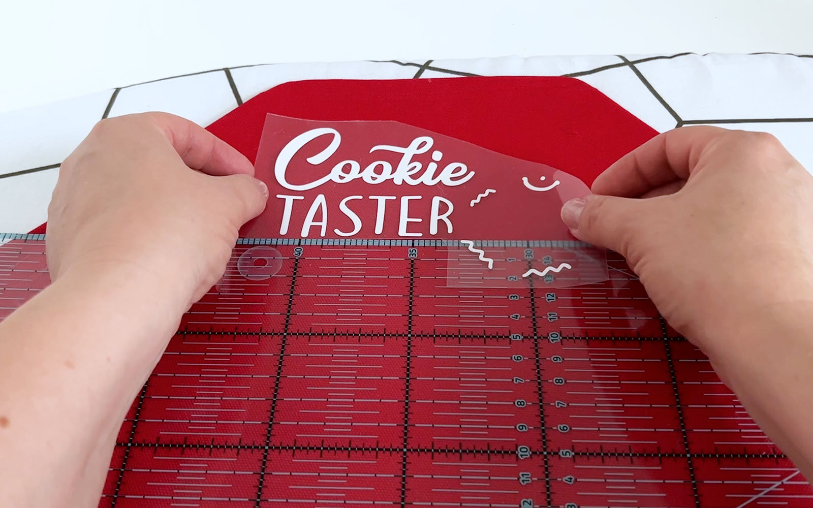 Placing white vinyl cutting onto red apron