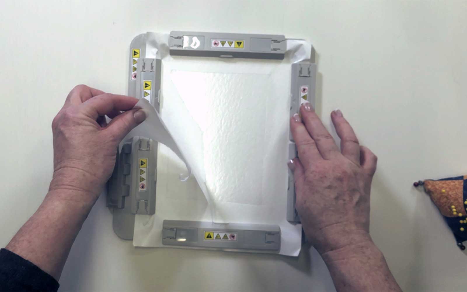 mani che tengono il telaio magnetico per ricamo Brother