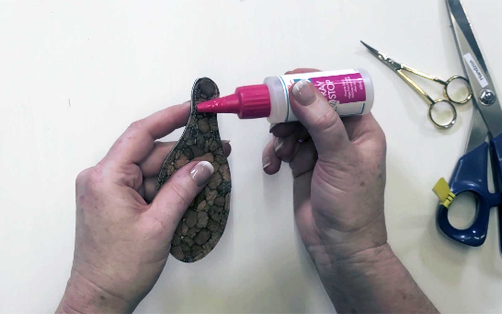 Hands applying liquid to black fabric