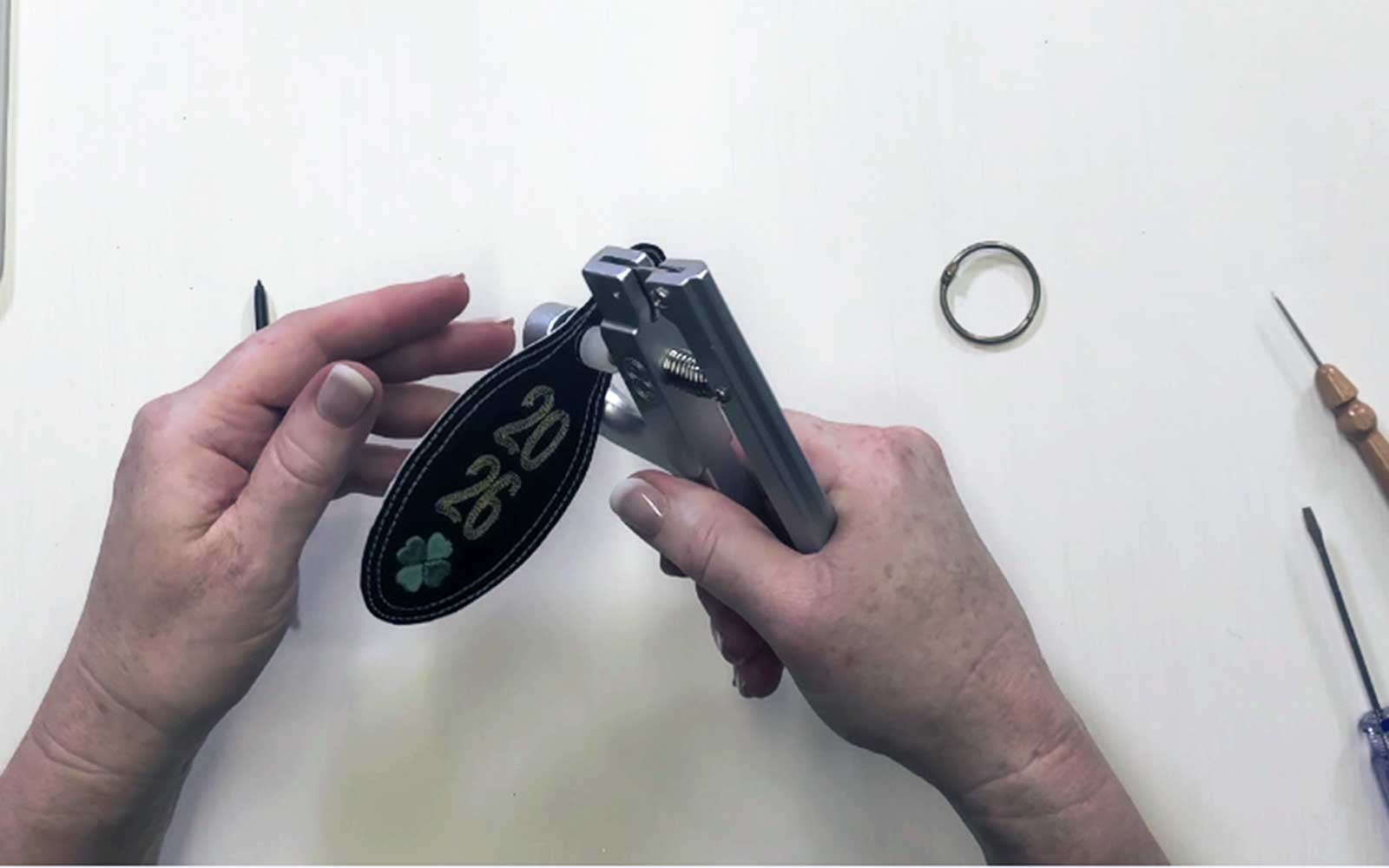 Press button tool attaching stud to embroidered key fob