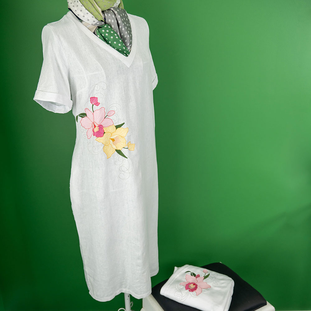 Leinenkleid mit Orchideenstickerei vor grüner Wand