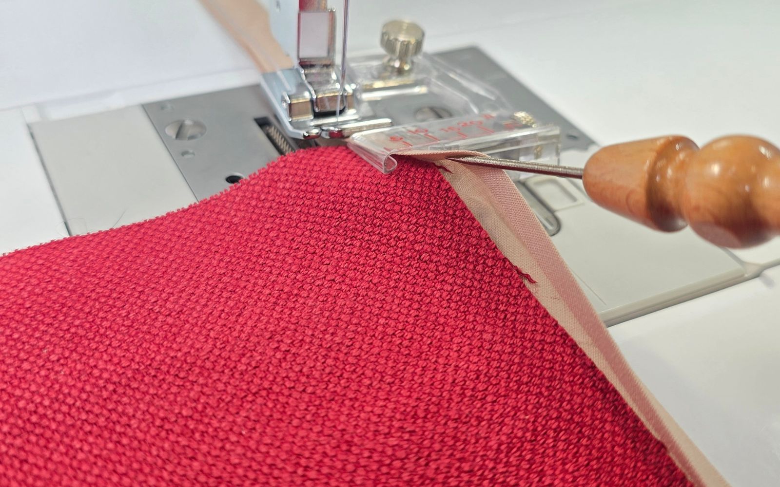 Tissu rouge avec poinçon dans le pied-de-biche pose biais réglable Brother