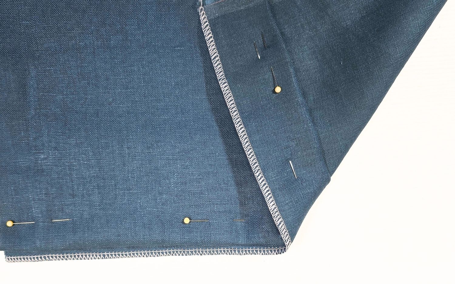 blind hem pinned on blue fabric with white stitching