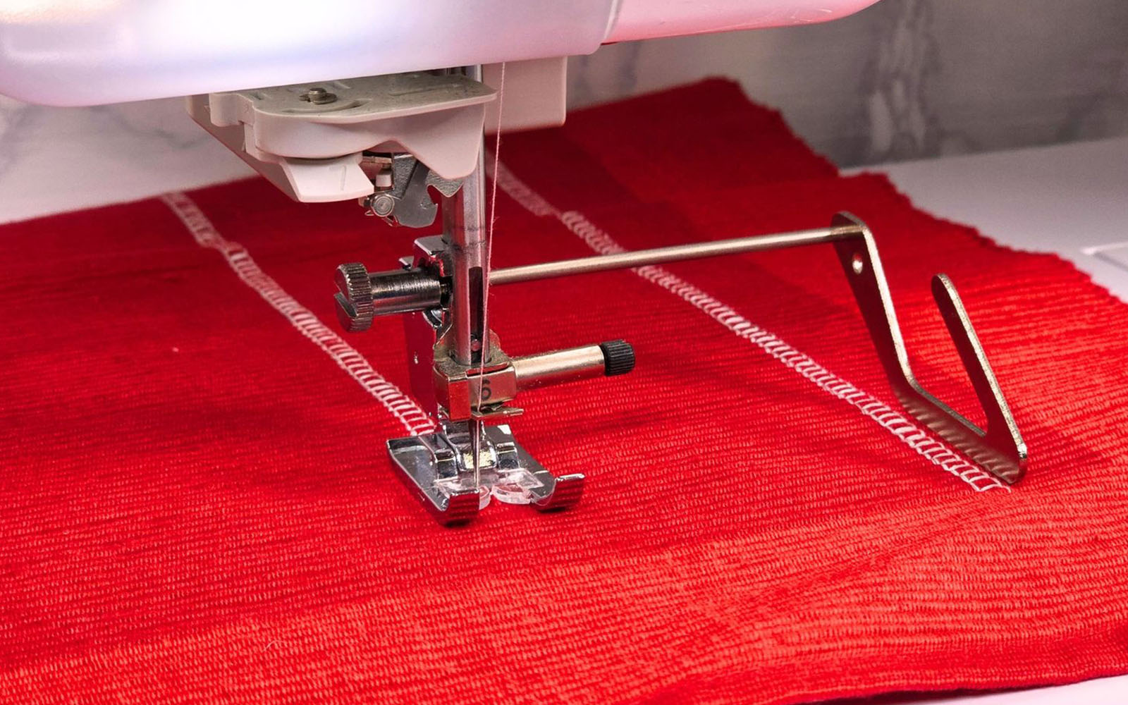 Brother quilting guide and white stitch on red fabric