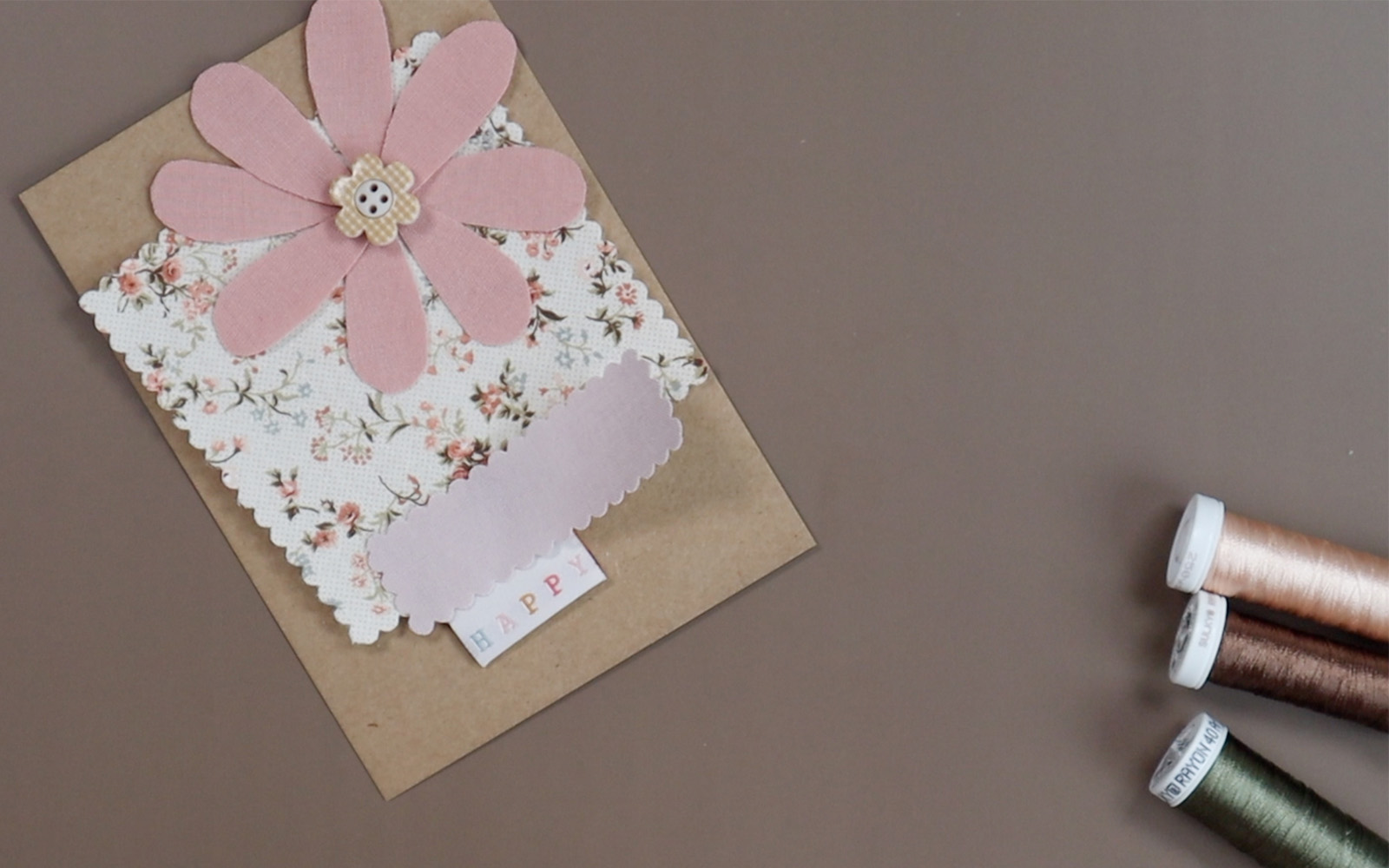 Fabric and thread elements of design laid out on card  