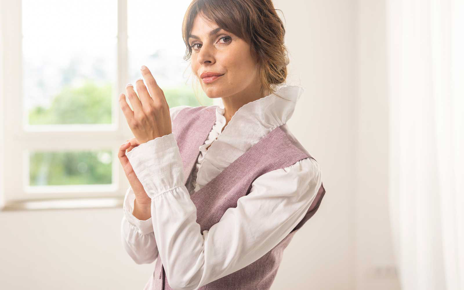 Woman wears white high-necked shirt and purple vest