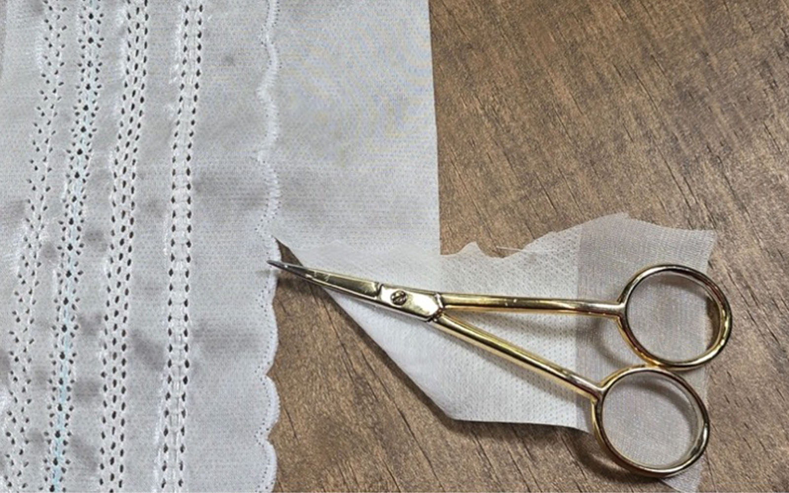 small scissors cutting sewn scalloped edge of fabric