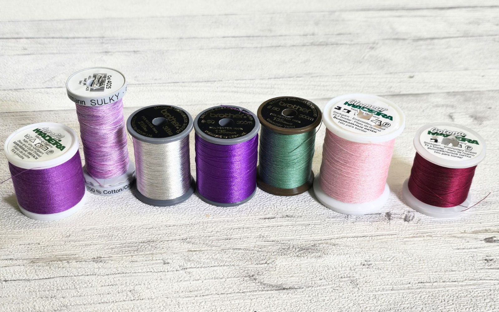 Sélection de fil pour machine à coudre dans les tons violets, roses et métallisés.